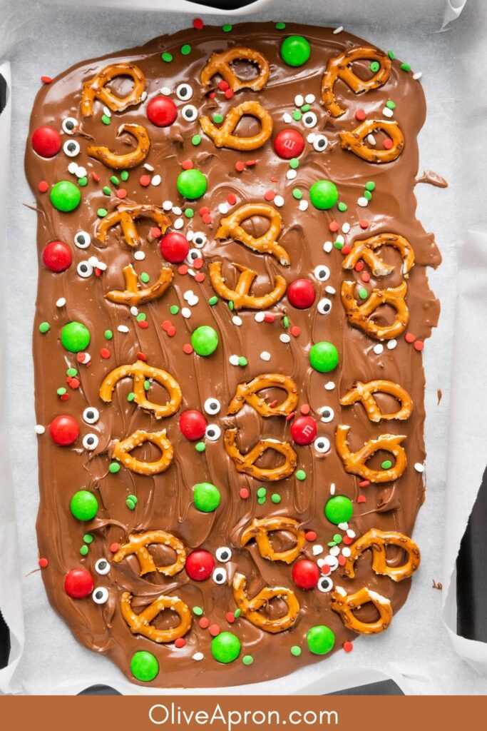 Chocolate bark topped with pretzels, red and green candies, and sprinkles.
