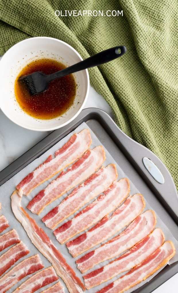 Bacon slices on a tray with a small bowl with maple syrup.