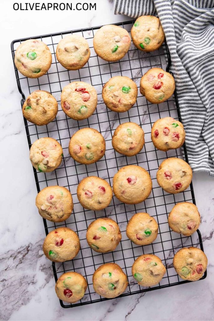Freshly baked Christmas M&M cookies with red and green candies cooling on a wire rack.