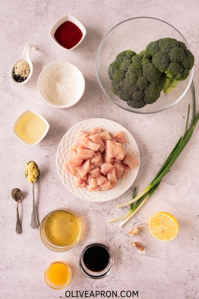 Fresh broccoli, diced raw chicken, garlic, soy sauce, honey, and other ingredients arranged on a kitchen counter.