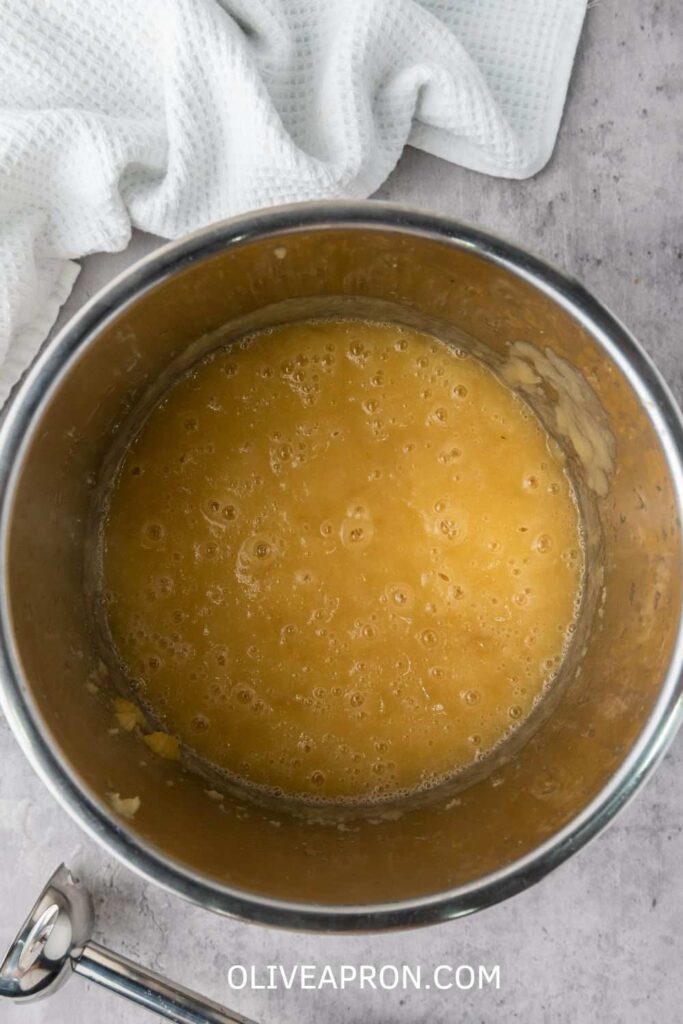 Smooth applesauce in an Instant Pot with a white towel nearby, freshly cooked and ready to serve.