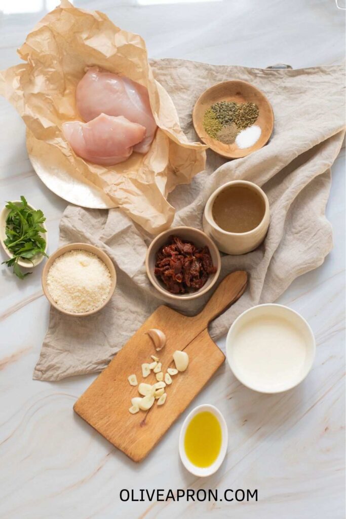 Merry Me Chicken ingredients including chicken breasts, sun-dried tomatoes, Parmesan, garlic, cream, and herbs.