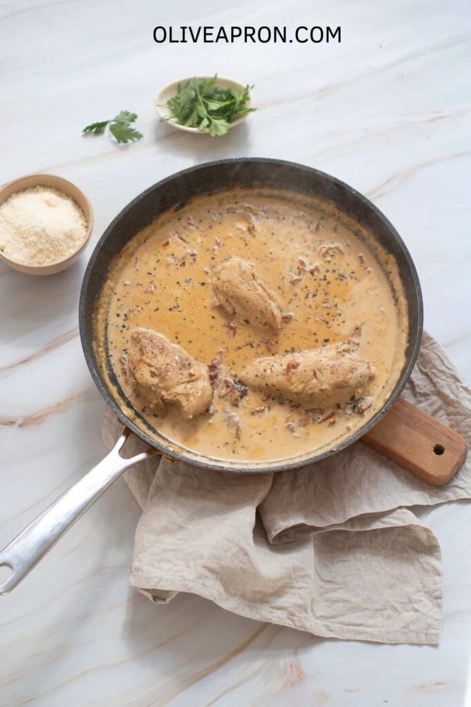 Creamy skillet with chicken breasts simmering in a rich sun-dried tomato sauce for Marry Me Chicken.