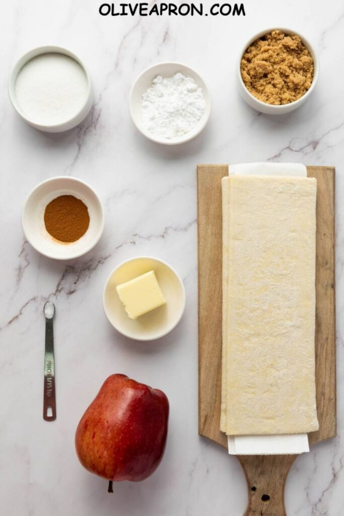 Ingredients for upside-down apple tarts including puff pastry, butter, apples, cinnamon, and sugar.