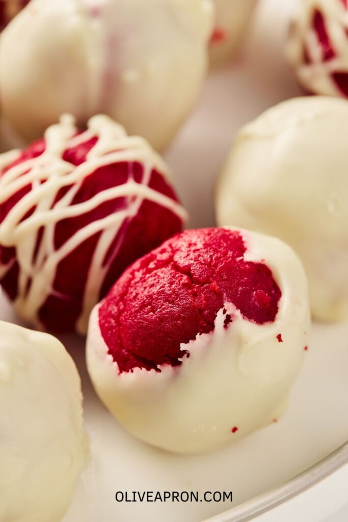 Overhead shot of red velvet truffles decorated with white chocolate drizzle.