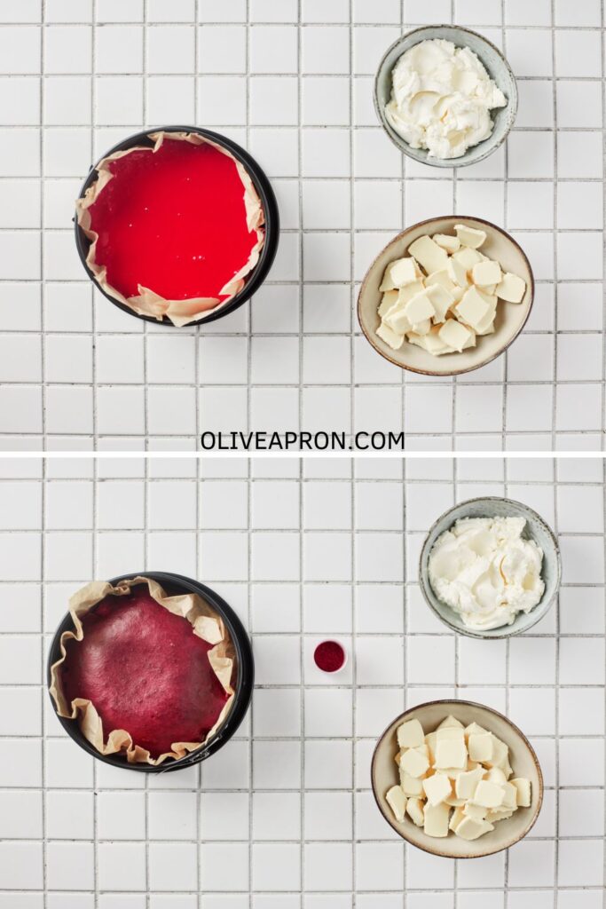 Red velvet cake baked in a lined pan next to bowls of cream cheese and chopped white chocolate on a tiled surface.