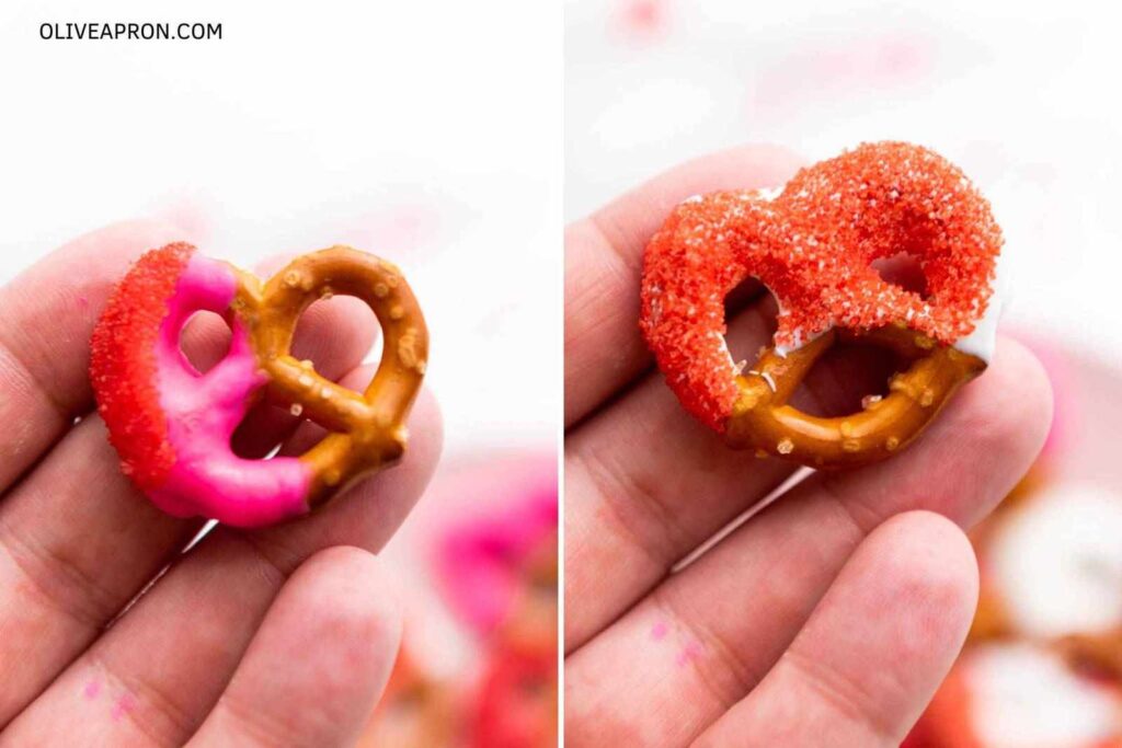 Handheld pink and red decorated Valentine pretzels close up.