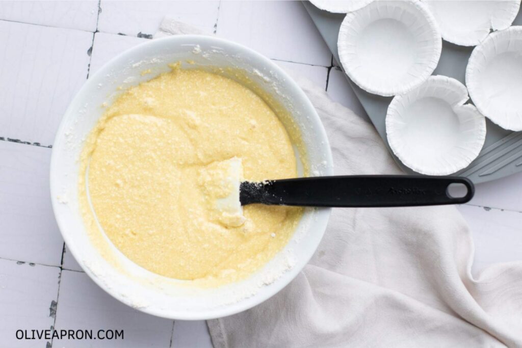 Smooth vanilla cupcake batter in a mixing bowl with a spatula, prepared for St Patricks Day cupcakes.