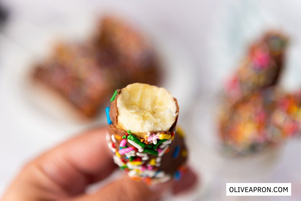 Close up of a hand holding a chocolate sprinkles covered banana