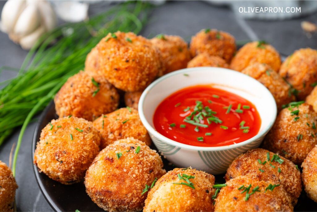 Mash potato bites served on a dish with tomato sauce