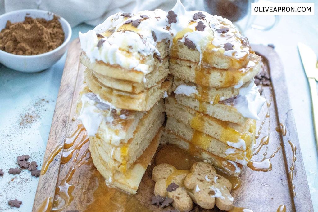 Fluffy gingerbread pancake stack with cream, syrup and gingerbread sprinkles