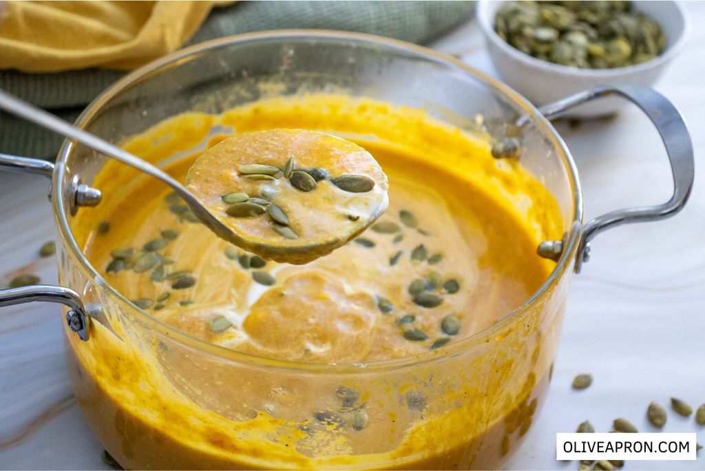 Close up pf Pumpkin soup with a serving spoon in a serving pot scattered with pumpkin seeds
